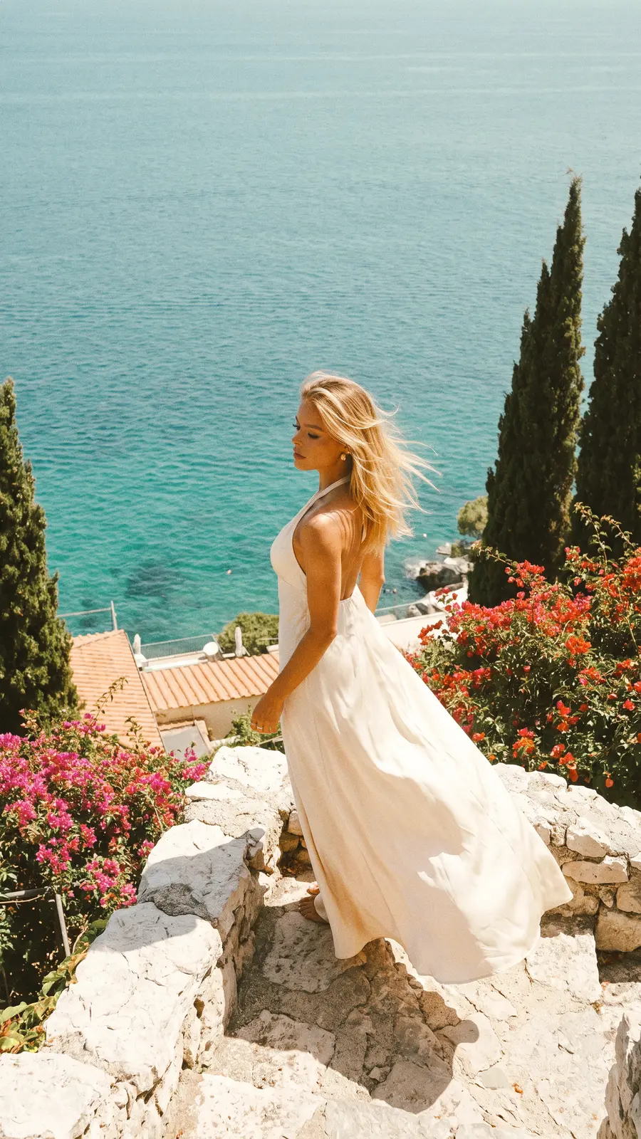 Mulher em um terraço de pedra sobre o mar Mediterrâneo, ao sol